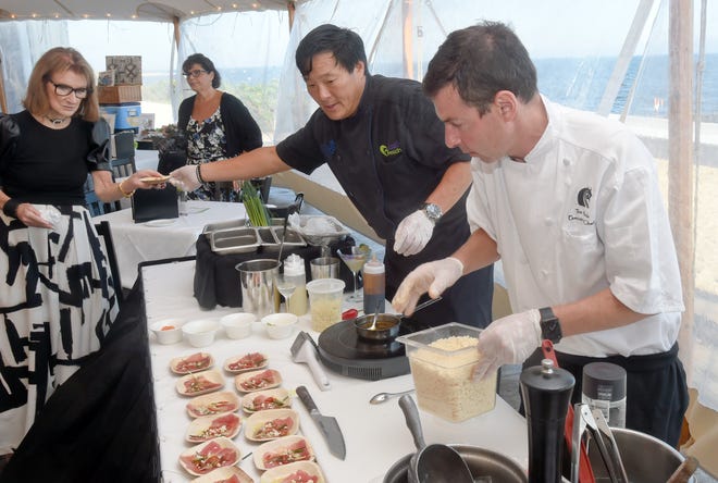 Janet Barbato (left), owner of The Ocean House restaurant, looks on as guest chef Ming Tsai (center) and Ocean House executive chef Tom Woods create appetizers for a recent reception to raise money for and awareness of Family Reach, an organization that supports families facing cancer.